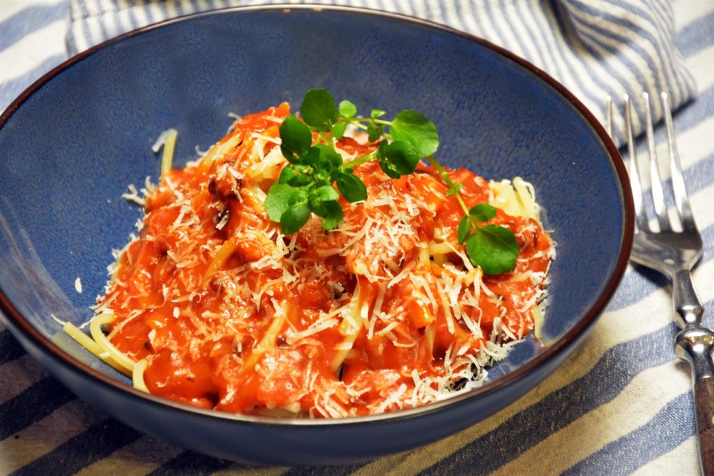 Wegetariański sos boloński z czarnej soczewicy beluga podany na spaghetti z tartym parmezanem