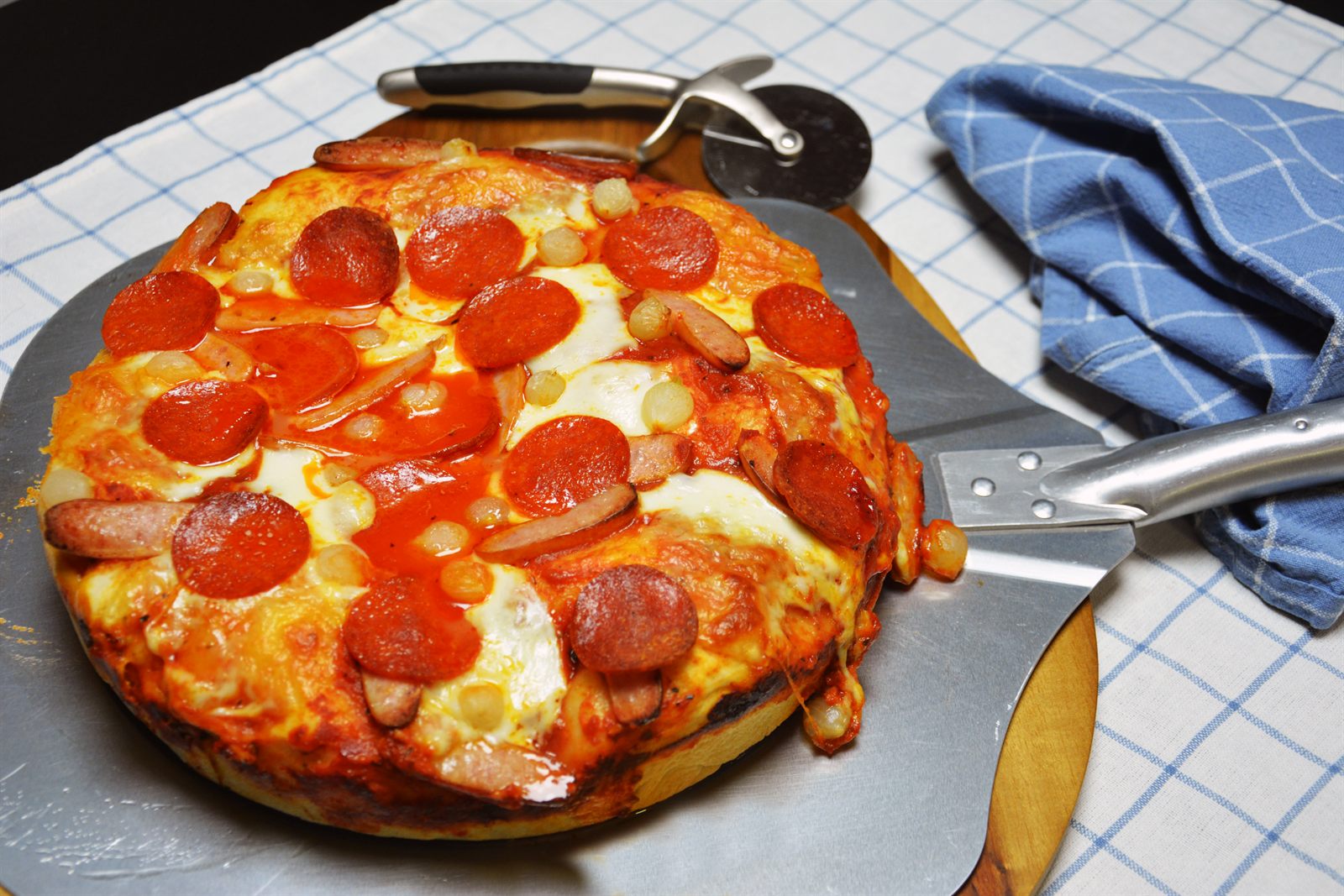 Domowa pizza na grubym cieście z roztopioną mozzarellą, pepperoni i marynowaną cebulką