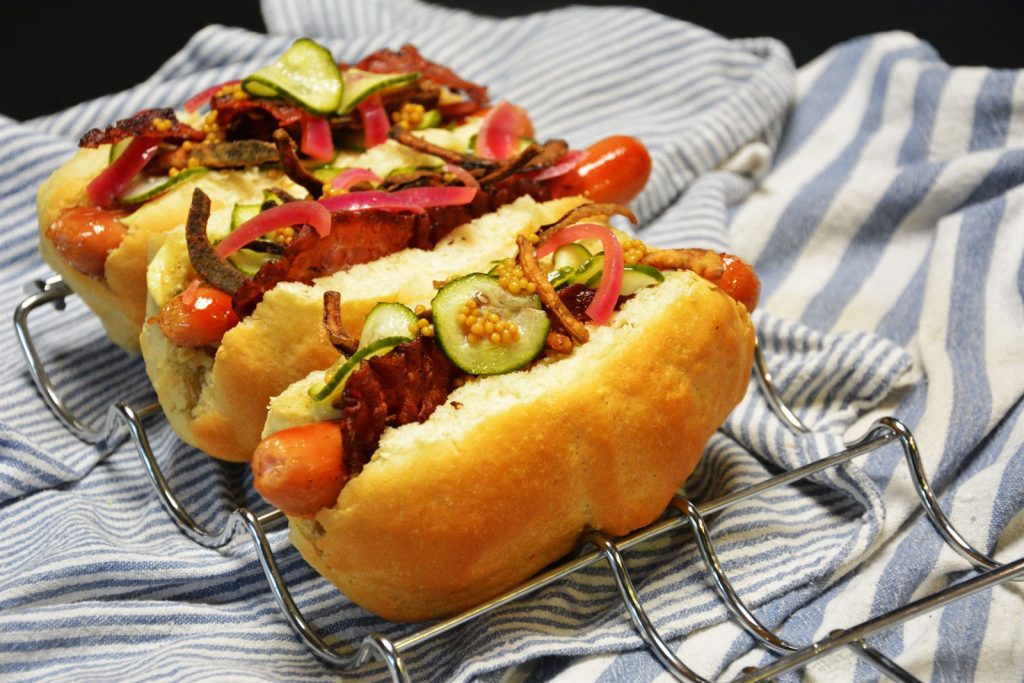 Hot dogi domowe z boczkiem, marynowaną czerwoną cebulą, prażoną cebulką, sałatką ogórkową i marynowanymi ziarnami gorczycy